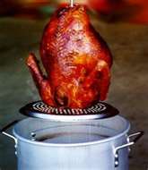 Hoist the fully cooked deep fried turkey out of the oil